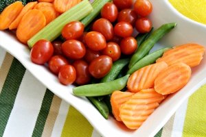 A veggie platter with carrot coins, sugar snap peas, and cherry tomatoes