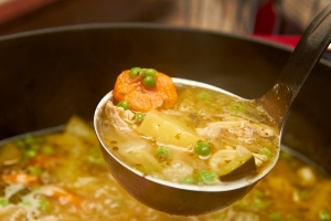 Chicken soup being ladled from a pot