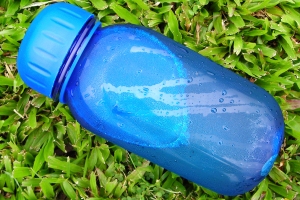 A blue reusable water bottle resting on the grass.