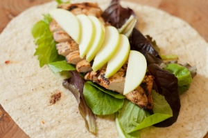 Apple slices and grilled chicken over lettuce in an open flour tortilla.