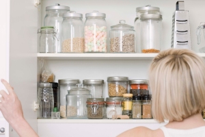 Woman looking into an organized kitchen cabinet.